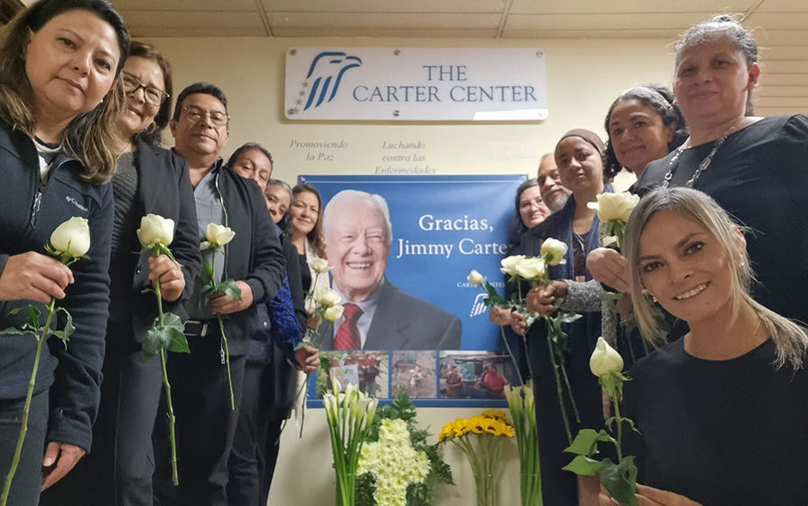 Smiling people hold up flowers.